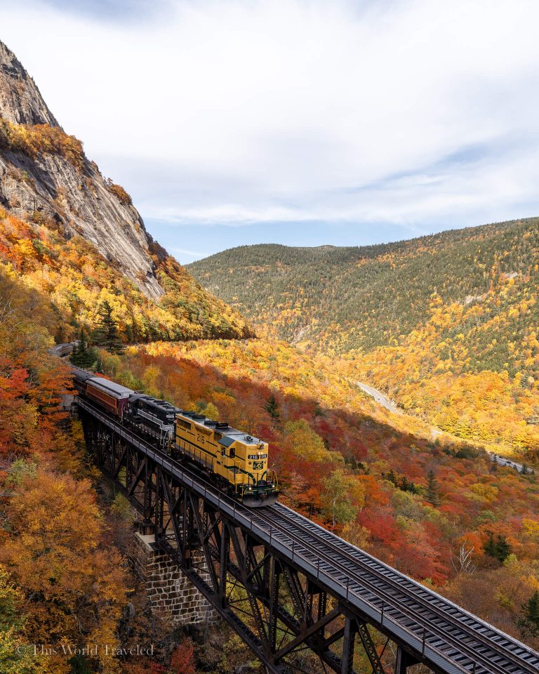 Train along the track extended over the Willey Brook Trestle in New Hampshire with views of yellow, orange and red leaves